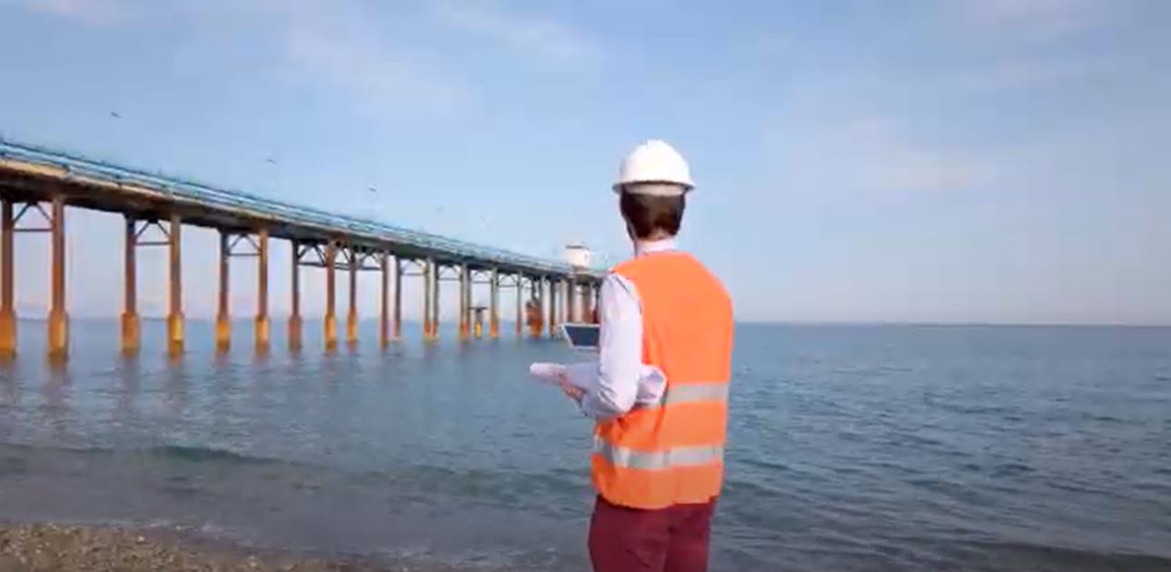Engineer on the beach near the pier stock video