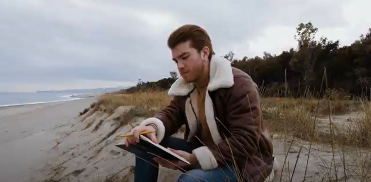 Young man reads a book by the sea stock footage